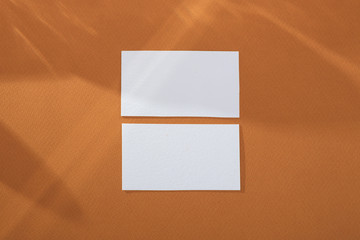 White empty business card mockup on brown background with abstract light from the wineglass