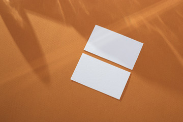 White empty business card mockup on brown background with abstract light from the wineglass