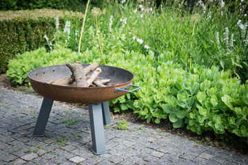 Portable fireplace at the backyard near garden of a house. A place for evening barbecue