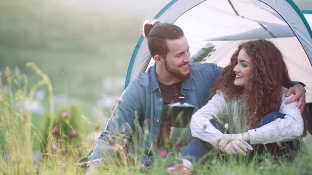 Young tourist couple travellers with tent shelter sitting in nature, resting.