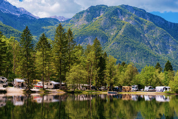 Scenery with camping of RV caravan trailers near Bohinj Lake in Slovenia. Nature and camper motorhomes in Slovenija. View of motor home van and green forest. Landscape in summer. Alpine Alps mountains - 294720924