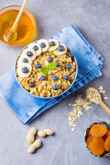 Oatmeal with berries and nuts. Breakfast: oatmeal, blueberries, banana and honey. Cooked oatmeal in bowl on blue napkin