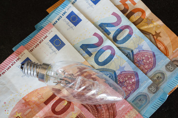 Euro banknotes and bulb as concept for the price of electricity