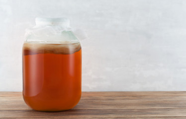 Kombucha tea mushroom in the glass jar on the wooden background.