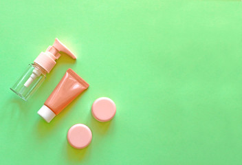 Сare cosmetic set of pink tube, boxes and bottle on a green background