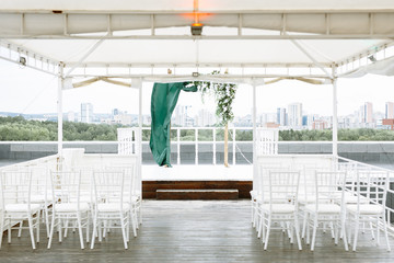 Wedding decor. Wooden arch for exit registration, with satin fabric in green emerald tones. The venue of the wedding ceremony on the roof overlooking the city.