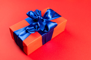 Christmas composition. Red gift box with a blue ribbon on a red background. View from above. a Christmas gift