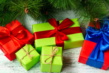 Christmas composition. Many multi-colored gift boxes under the Christmas tree on a wooden floor near fir branches. View from above. a Christmas gift