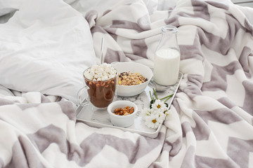 Tray with tasty breakfast on bed