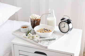 Tray with tasty breakfast on bedside table