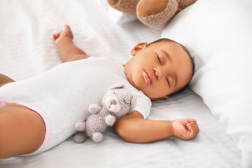 Cute African-American baby sleeping on bed