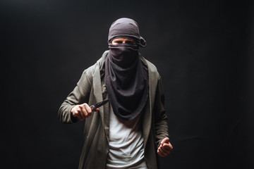 Naklejka na ściany i meble criminal in a mask threatens with a knife the dark background