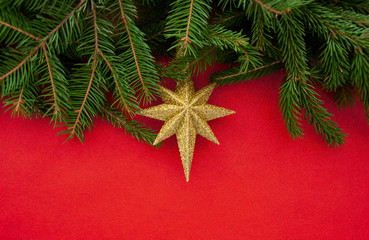  Texture and background for New Year and Christmas.Golden star and Christmas tree branches on a red background.