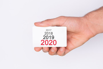 Progression from 2017 to 2020. Hand holding a white card . White background. Copy space