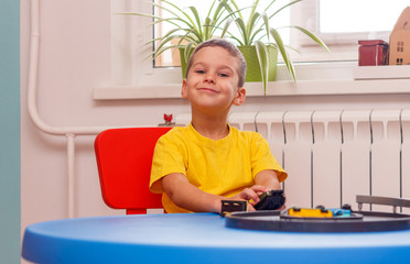 Little boy in yellow t-shirt playing with cars and toys at home, indoor