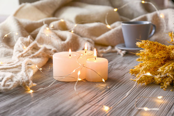 Christmas lights, burning candles and plaid on window sill