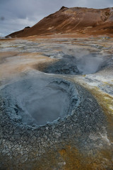 Boiling mudpots in the geothermal area Hverir and cracked ground around, Iceland in summer. Myvatn region, North part of Iceland