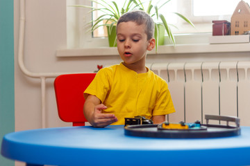 Little boy in yellow t-shirt playing with cars and toys at home, indoor