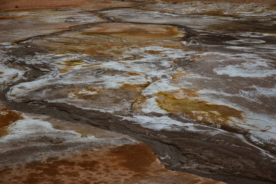 Solfatare mudpot s in the geothermal area Hverir, Iceland. The area around the boiling mud is multicolored and cracked.