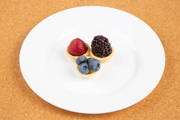 Blackberry, blueberry and strawberry in a waffle basket on a white plate. Vitamins and wholesome foods