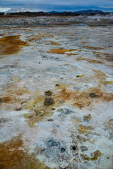 Closeup of solfatare mudpot s in the geothermal area Hverir, Iceland. The area around the boiling mud is multicolored and cracked.