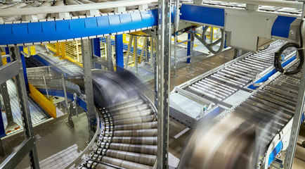 Picture of a transportation line conveyor roller with containers in motion.