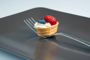 Strawberries and blueberries with cream in a fork on a plate. Vitamins and Nutrition
