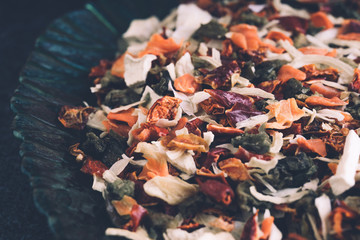 Seasoning a mixture of dried vegetables in a plate on a black background. Spices and seasoning for cooking