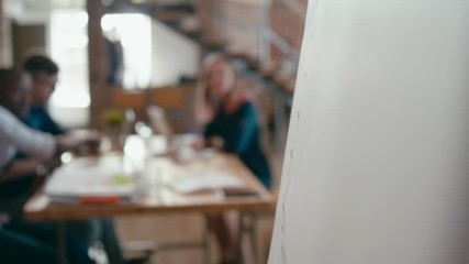 Close Up of Female Hand Writing by Marker on White Flipchart Board in Office at Team Meeting, Seminar or Business Presentation. Woman is Drawing Increasing Graph. 4K Corporate Static Shot