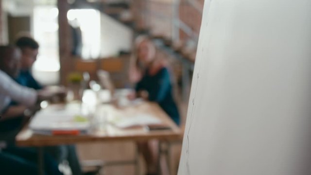 Close Up of Female Hand Writing by Marker on White Flipchart Board in Office at Team Meeting, Seminar or Business Presentation. Woman is Drawing Increasing Graph. 4K Corporate Static Shot