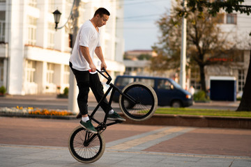 A young guy on a BMX bike, wraps the steering wheel in a jump.