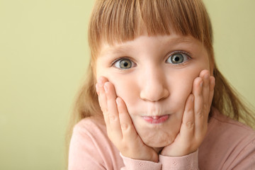 Grimacing little girl on color background, closeup