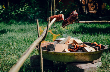 Obraz premium Roasting sausages on the fire. The concept of spending free time outdoors. Lighting a bonfire made of wood. Safe lighting a bonfire, roasting sausages, making a barbecue. Fire.
