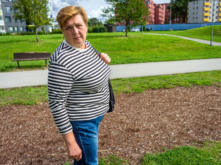 Mature woman in striped shirt walks in Park