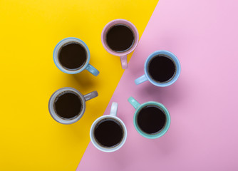 Coffee in the different cups on the pink and yellow background. Flatlay, cheerful day concept