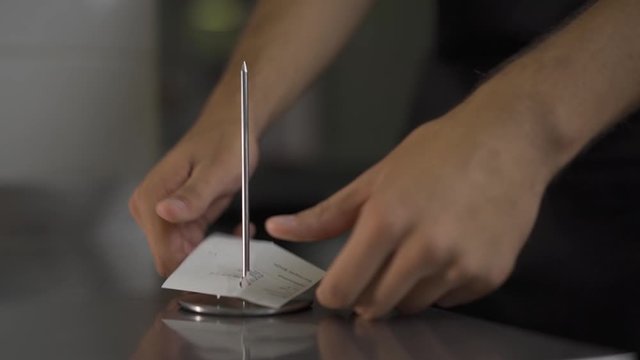 At Your service. Waiter brings order to the kitchen. Then pin it on the metal stick. Well-known tradition.