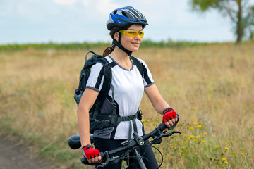 Beautiful girl cyclist with a bicycle on the nature. Healthy lifestyle and sport. Leisure and hobbies