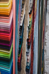 Many fabrics of different types. Colorful fabric swatches on shopfront. Textile samples background.