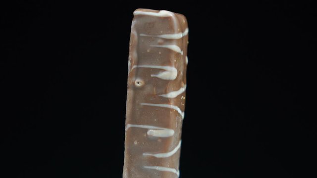 Chocolate bar rotates in front of black background