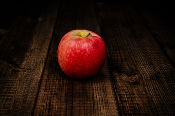 Red apple on a dark wooden table. The concept of eating fruit, eating meals with vitamins. Taking care of yourself, diet. Healthy food, apples.
