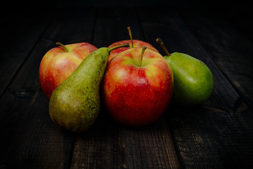 Red apples with pear on a dark wooden table. The concept of eating fruit, eating meals with vitamins. Taking care of yourself, diet. Healthy food, apples, pears.
