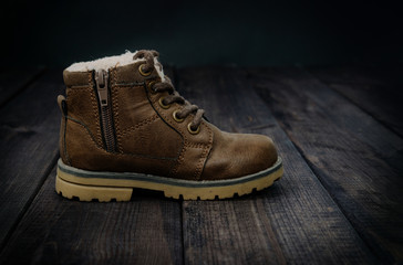 Leather, children's shoe on wooden table. The concept of upcoming cold, selling shoes. Warm, comfortable shoe for children with fur at an angle and inclination.