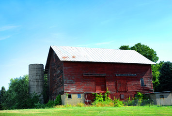 Obraz premium Cracked and Peeling Red Paint Clings to Wooden Barn
