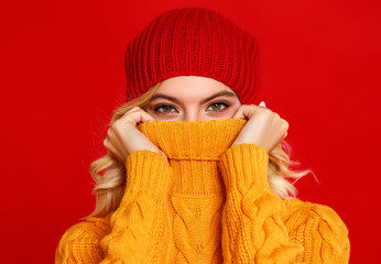 happy emotional cheerful girl laughing  with knitted autumn cap  on colored red background