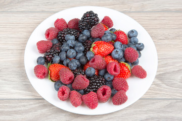 Blackberry, raspberry blueberry and strawberry on a white plate. Vitamins and wholesome foods