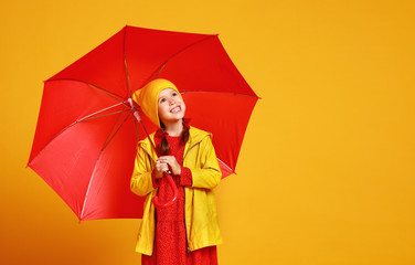 young happy emotional cheerful child girl laughing  with red umbrella   on colored yellow background.