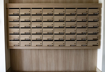 Closeup of numbered mailboxes and lockers in raw in the condo. Natural wooden letterbox panel...