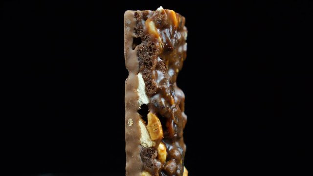 Muesli covered in chocolate, healthy eating chocolate bar rotates on a black background.