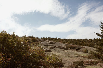 Hiking in Acadia National Park along granite bedrock of Cadillac Mountain on a cool Fall day.