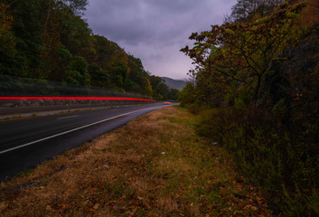Stormy autumn evening at Storm King Park New York, featuring car light trails on the foreground and moody sky on the background